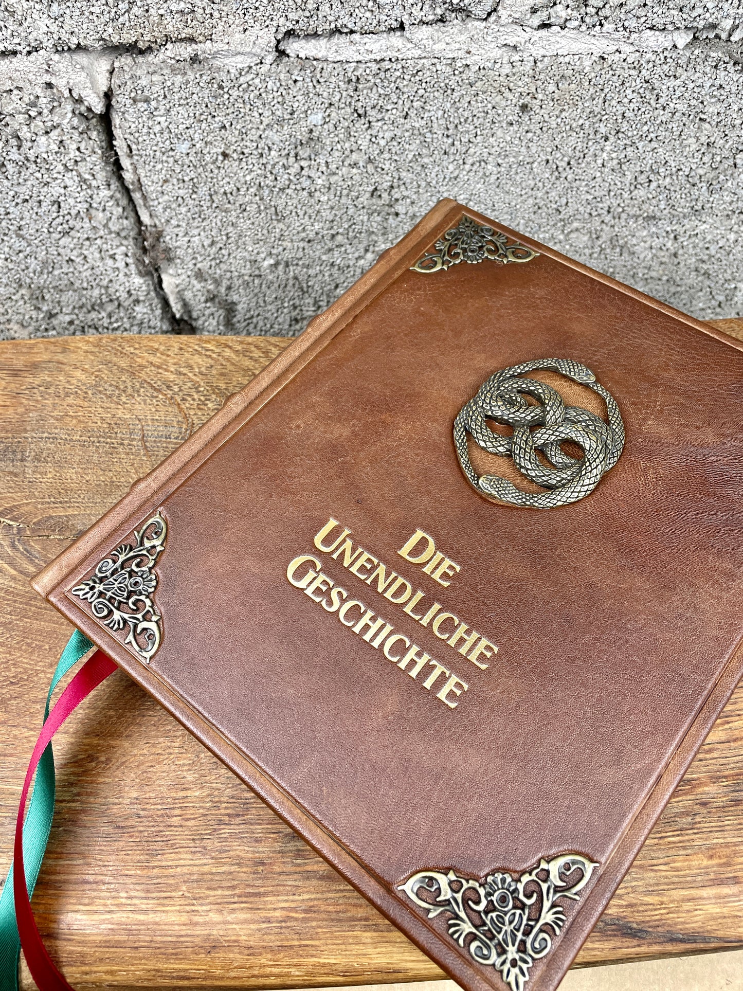 Große Lederausgabe der Unendlichen Geschichte mit AURYN-Emblem auf der Vorderseite, goldene Titelprägung und zwei breite Satin-Lesebänder in Rot und Grün.