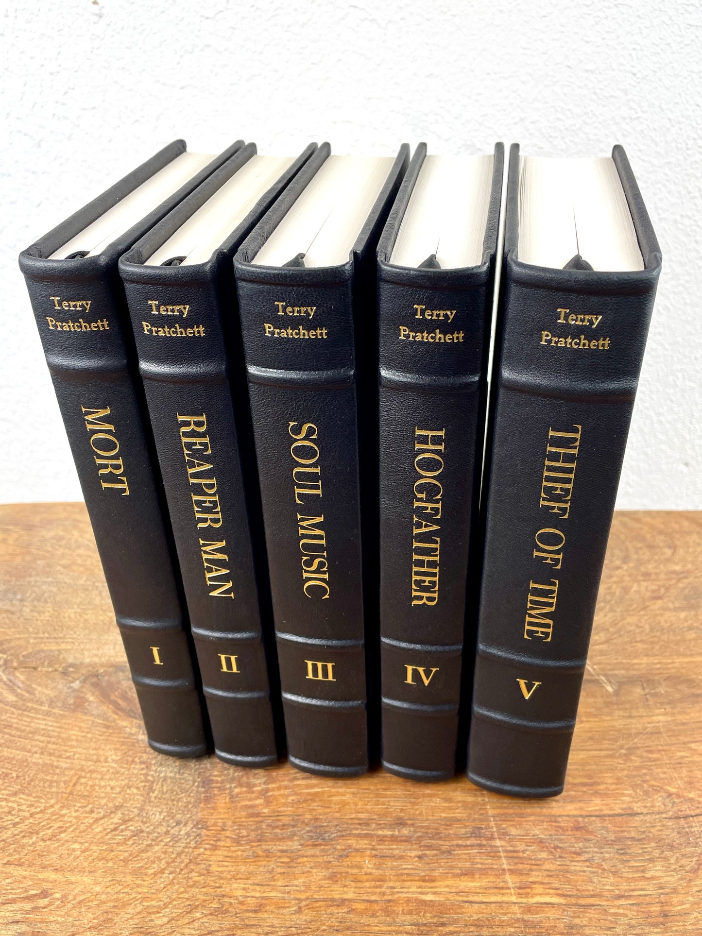 Fünf handgebundene Bände der Terry Pratchett Death Series in schwarzem Lammleder mit goldener Prägung.