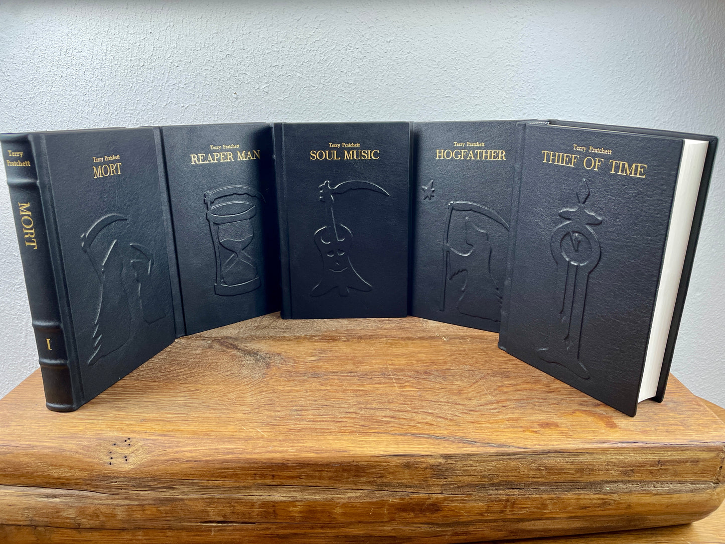 Fünf handgebundene Bände der Terry Pratchett Death Series in schwarzem Lammleder mit goldener Prägung.
