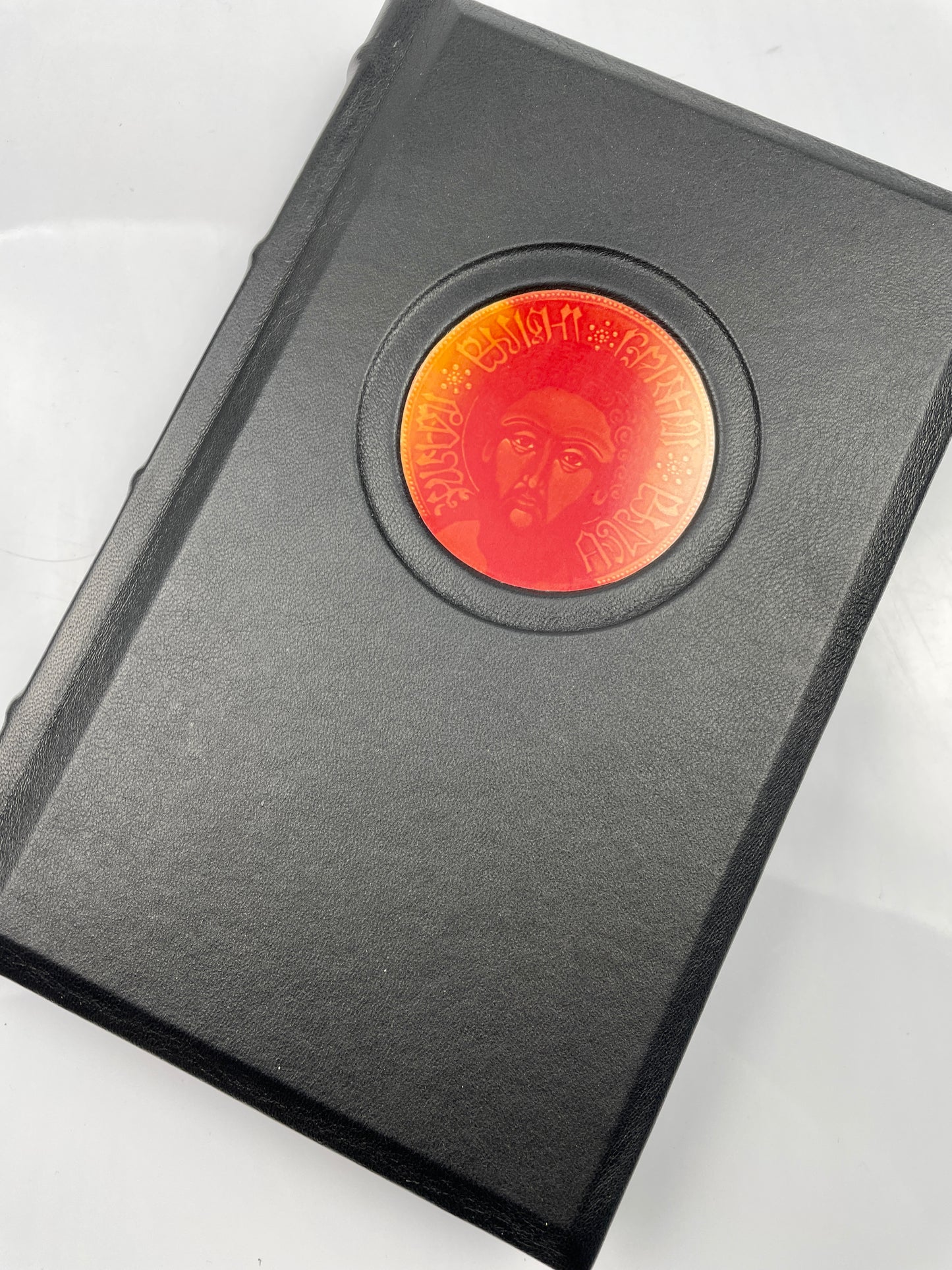 Top view of the black leather cover of 'Cyprian of Antioch' by Frater Acher, featuring an icon of Cyprian.
