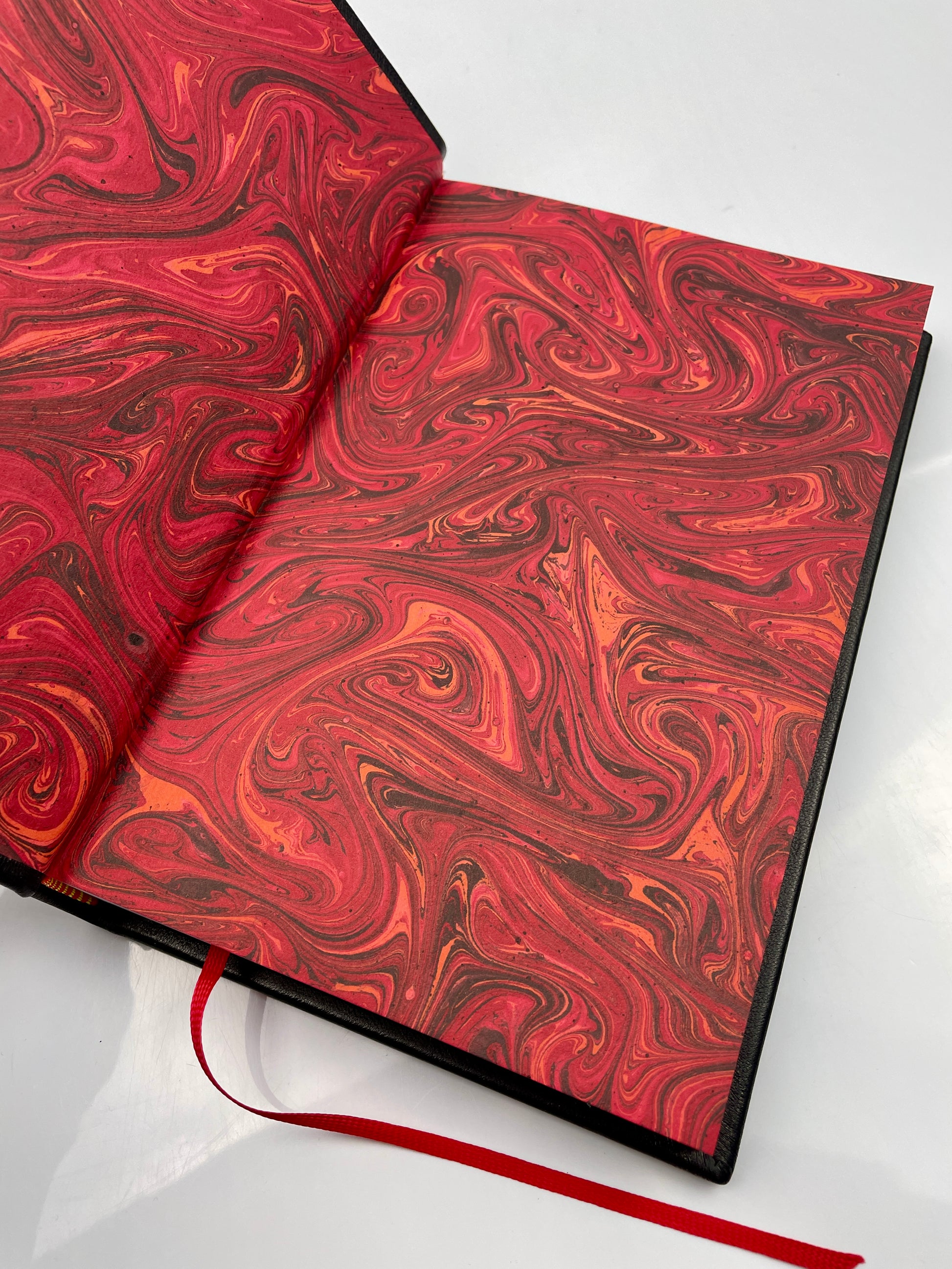 Open view of 'Cyprian of Antioch' book showcasing black-red marbled endpapers, highlighting the craftsmanship and unique design of the binding.