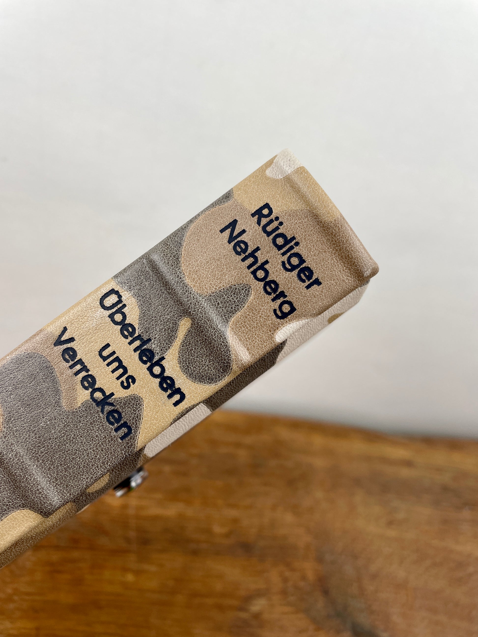 Ledereinband des Survival-Handbuchs von Rüdiger Nehberg in camouflagefarbenem Leder.